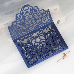 Detail showing deep blue laser-cut wedding invitation with intricate floral lace patterns