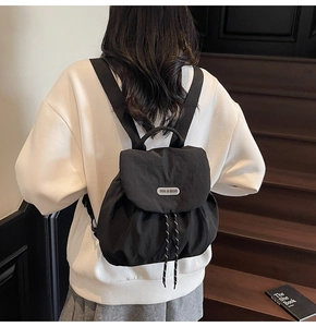 Detailed back view of a chic black nylon backpack with flap and drawstring closure