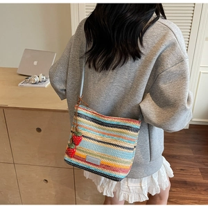 Détail d'un sac seau tissé à rayures colorées avec de jolis charms fraises rouges