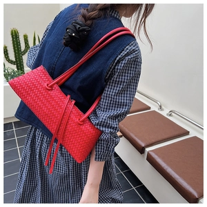 Detail shot of a vibrant red woven shoulder bag showcasing the intricate leather texture