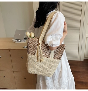 Detailed close-up of woven straw tote bag with wood bead tassel and hollow-out mesh pattern