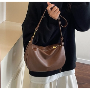 Detail of brown lychee grain leather dumpling bag with golden heart zipper charm
