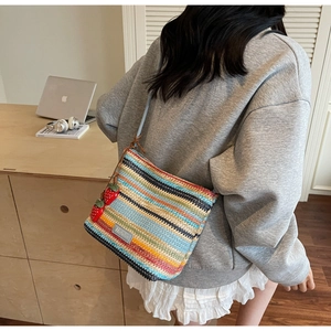 Gros plan d'un sac seau tissé coloré avec des breloques fraises et une étiquette en cuir