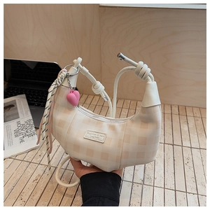 Detail showing beige checkerboard crescent bag with heart charm and knotted handle