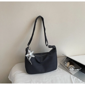 Detail of black canvas crescent tote bag with silver star charm and zipper closure