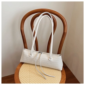 Close-up of white woven leather underarm bag with zipper on a vintage wooden chair