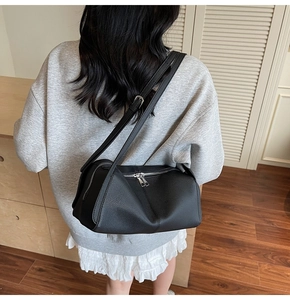 Close-up of black lychee grain leather pillow bag with double zippers and soft texture
