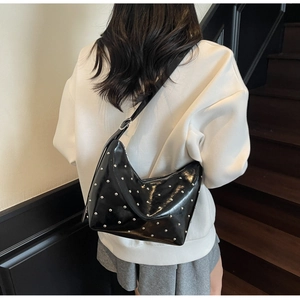 Detailed back view of model wearing black studded crescent bag over a white hoodie