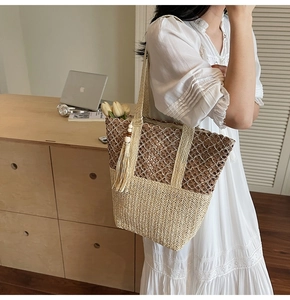 Detail of a woven straw tote bag with brown tassels and a large capacity beach style