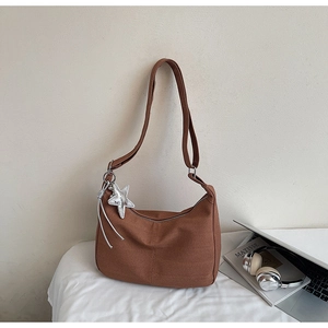 Detail view of brown canvas hobo bag with silver star pendant and wide shoulder strap