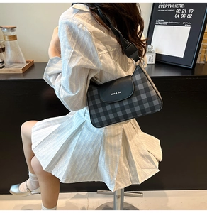 Detailed close-up of a plaid shoulder bag featuring black leather flap and silver buckle