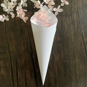 White wedding paper cone with pink and white flower petals on dark wood background