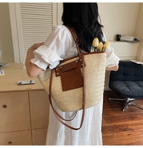 Detail of large straw tote bag with brown leather stitching and front pocket flap
