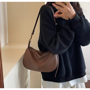 Close-up of brown litchi leather hobo bag with embossed logo and gold metal buckle