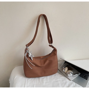 Detail of brown hobo bag showing fabric texture, star charm, and adjustable strap