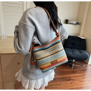 Détail du sac seau tissé à rayures avec breloques fraises et bandoulière en cuir marron