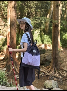 Outdoor action shot of woman with contrast color drawstring backpack in a forest