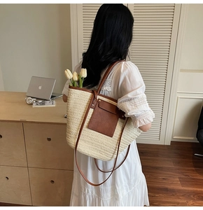 Detail of straw woven bucket bag with brown leather handles and interior flower decor