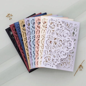 Macro view of laser-cut wedding invitations in multiple colors with floral patterns