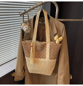 Detail of woven straw tote bag with brown cutout mesh and beige fringe tassel