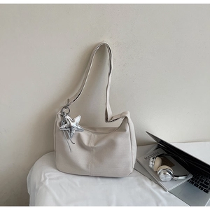 Minimalist beige hobo bag with star pendant detail next to artistic laptop and headphones
