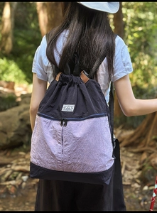 Outdoor view of a lightweight nylon drawstring backpack with color-blocking and leather handle