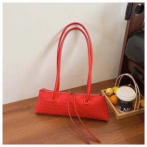Detail of red woven leather handbag featuring intricate cross-braid texture and long straps