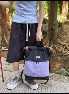 Detail of a casual drawstring backpack in black and lavender with leather accents