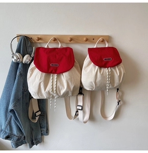 Detailed comparison of large and small red and white contrast backpacks hanging on a wall