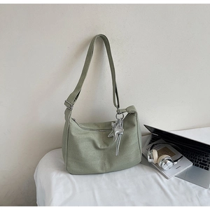 Detail of light green tote bag with V-shaped woven texture and silver star charm pendant
