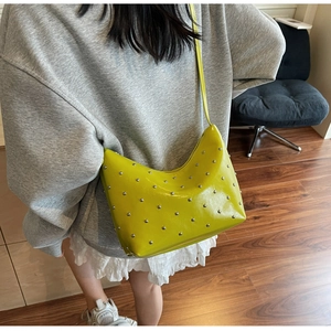 Detail of lime green crescent shoulder bag featuring silver metal rivets and glossy finish