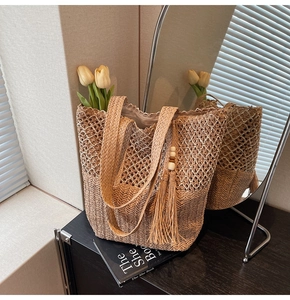 Detail of the straw tote bag showing woven texture with tassels and wood beads