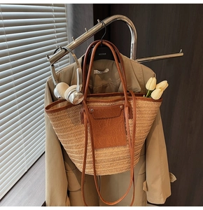 Close-up of a large straw tote bag with brown leather handles and a yellow tulip decoration