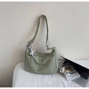 Detail of light green dumpling tote bag with striped texture and star charm accessory