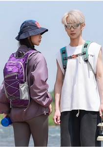 Outdoor backpack detail showing bungee cords and side mesh pocket in natural sunlight