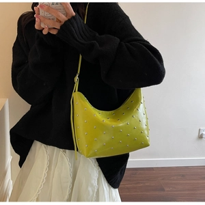 Model wearing bright green hobo bag with silver rivets and glossy leather finish