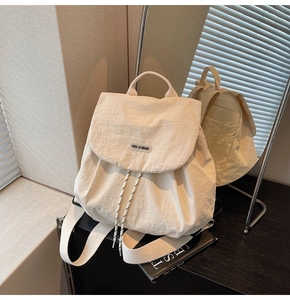 Detail view showing beige nylon backpack texture with drawstring closure and brand logo