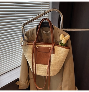 Detail of cream woven straw tote with brown leather pocket and handles on a trench coat