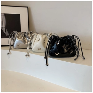 Trois sacs seaux en argent, crème et noir avec breloques papillon et bandoulières chaînes
