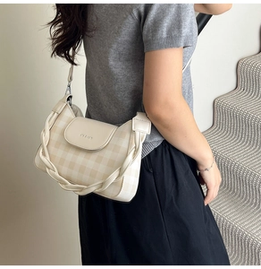 Detail of beige checkered crossbody bag featuring a braided strap and metal buckle closure