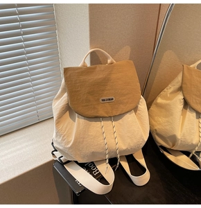 Detail of minimalist beige and brown patchwork backpack with drawstrings and logo patch
