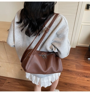 Dettaglio di una borsa pillow in pelle marrone con doppi cinturini e trama a grana