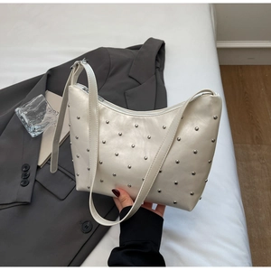 Detail of cream white leather hobo bag with silver metal rivets and shoulder strap