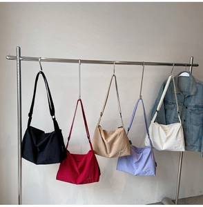 Detail showing five colors of large capacity nylon bags on a rack with a wide strap