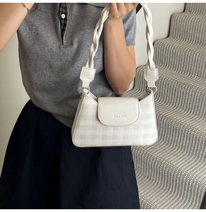 Detail of cream plaid shoulder bag with unique braided handle and embossed flap closure