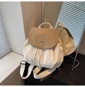Detail of cream nylon backpack with khaki flap and drawstring closure in natural light