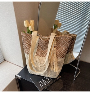 Detail of woven straw tote bag with long shoulder strap and decorative fringe tassel