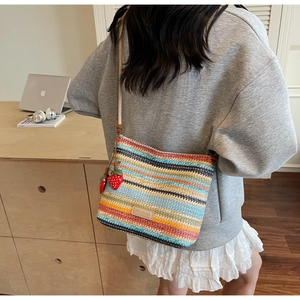 Détail du sac seau tissé avec rayures colorées et charmant pendentif fraise