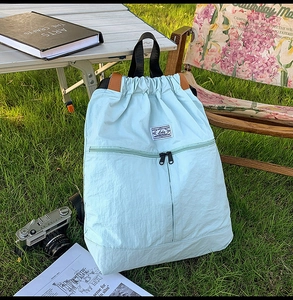 Detail of mint blue nylon backpack with unique T-shaped zipper pockets in outdoor camp setting