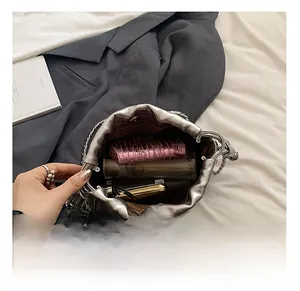 Vue intérieure du sac seau argenté avec accessoires quotidiens et fermeture à cordon